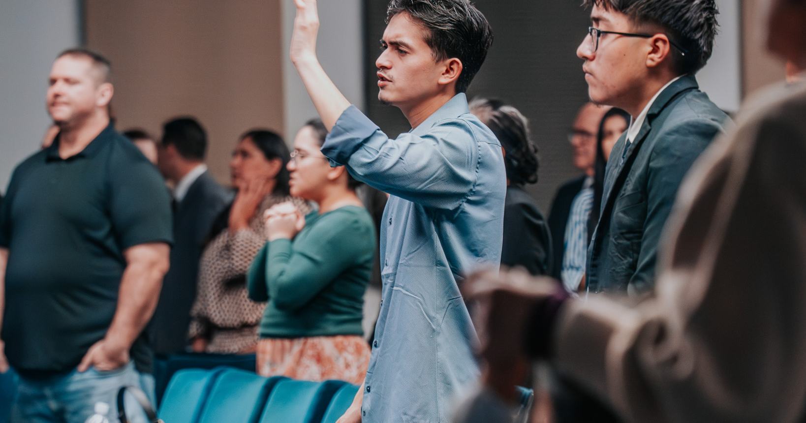 A young man lifting his hand in praise during worship at Praise Tabernacle Las Vegas